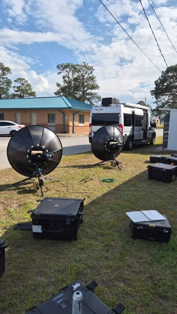 Campervan parked outdoors with equipment cases and filming equipment nearby