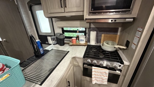 RV kitchen with sink, gas stove, microwave, countertop, and overhead cabinets