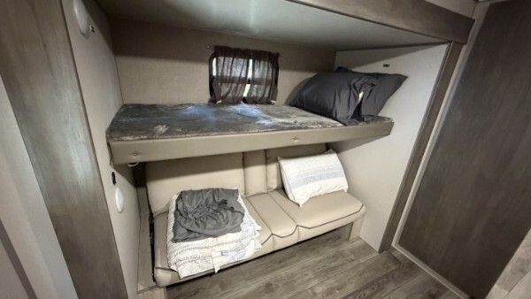 RV bunk room with upper bunk bed and convertible sofa for extra sleeping space