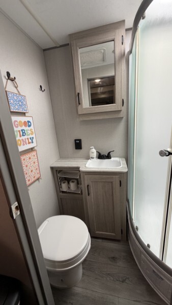 Compact RV bathroom with sink, mirror cabinet, toilet, and shower