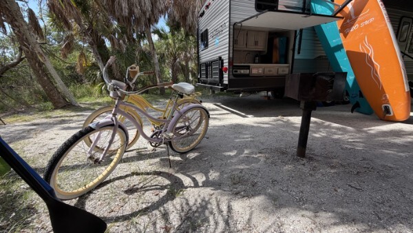 RV parked at a campsite with bicycles and paddleboards for outdoor adventure