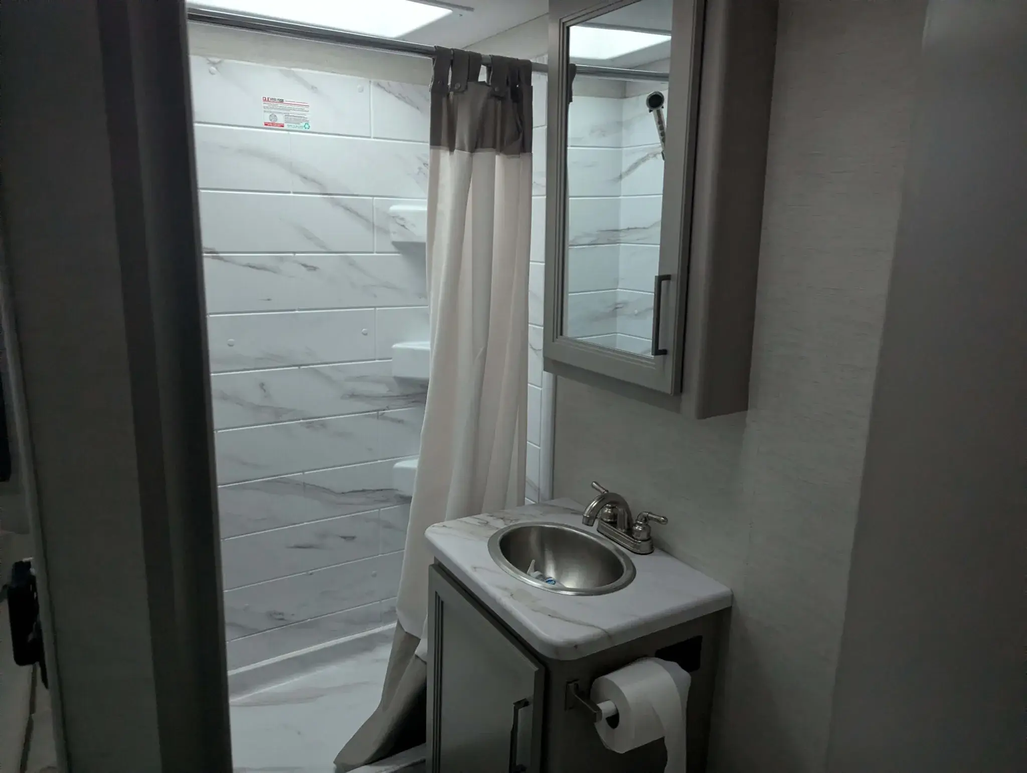 Campervan bathroom with shower, sink, toilet, and storage